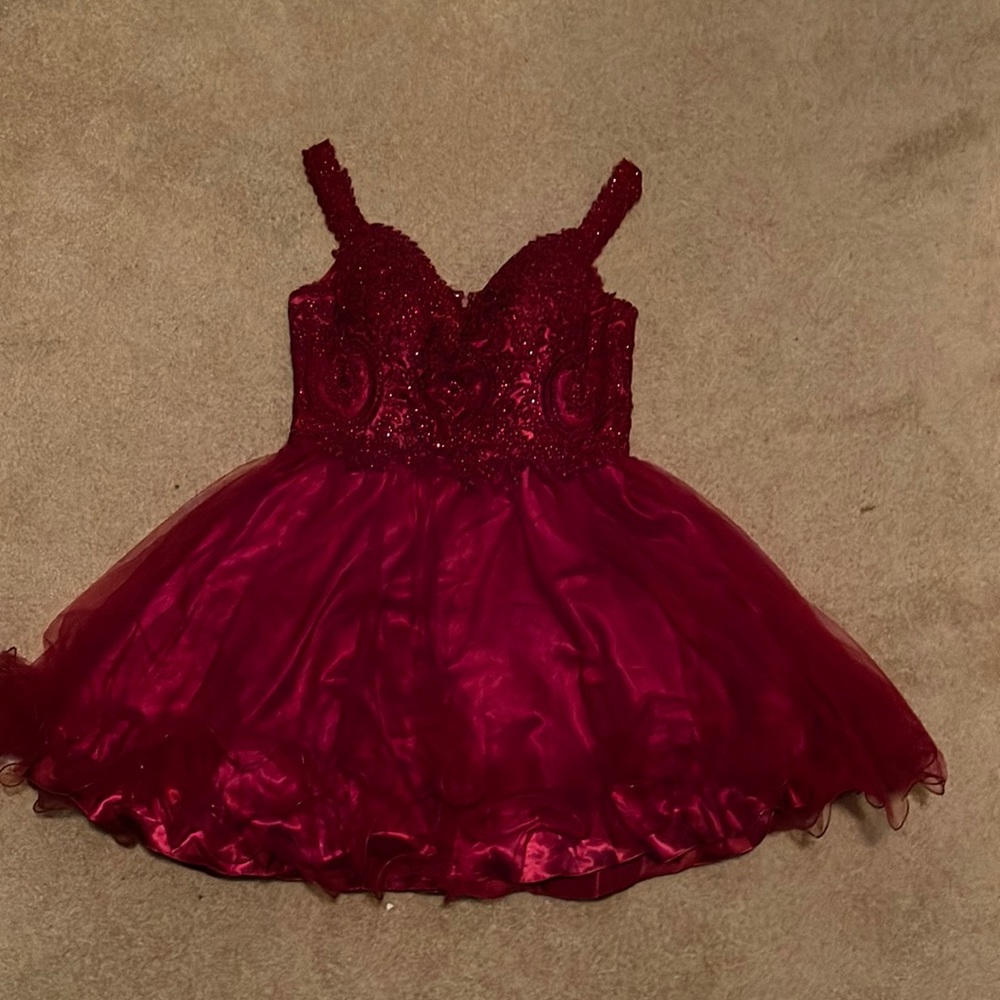 A quinceñera dama dress in burgundy with a zipper in the back and padded top.